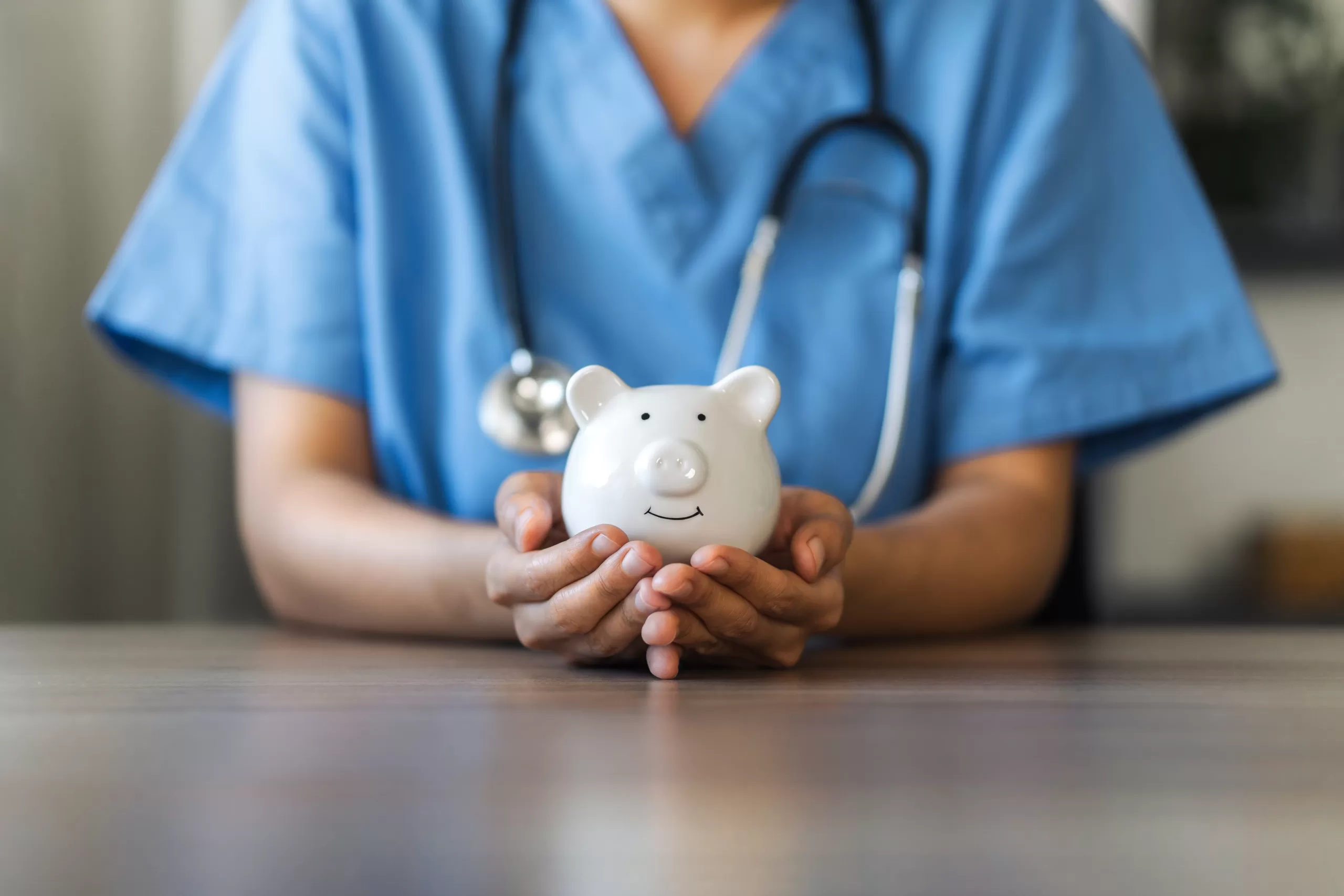 Occupational Health cost savings - A woman in a nurse uniform holding a clay piggy bank in her hands resting on a table